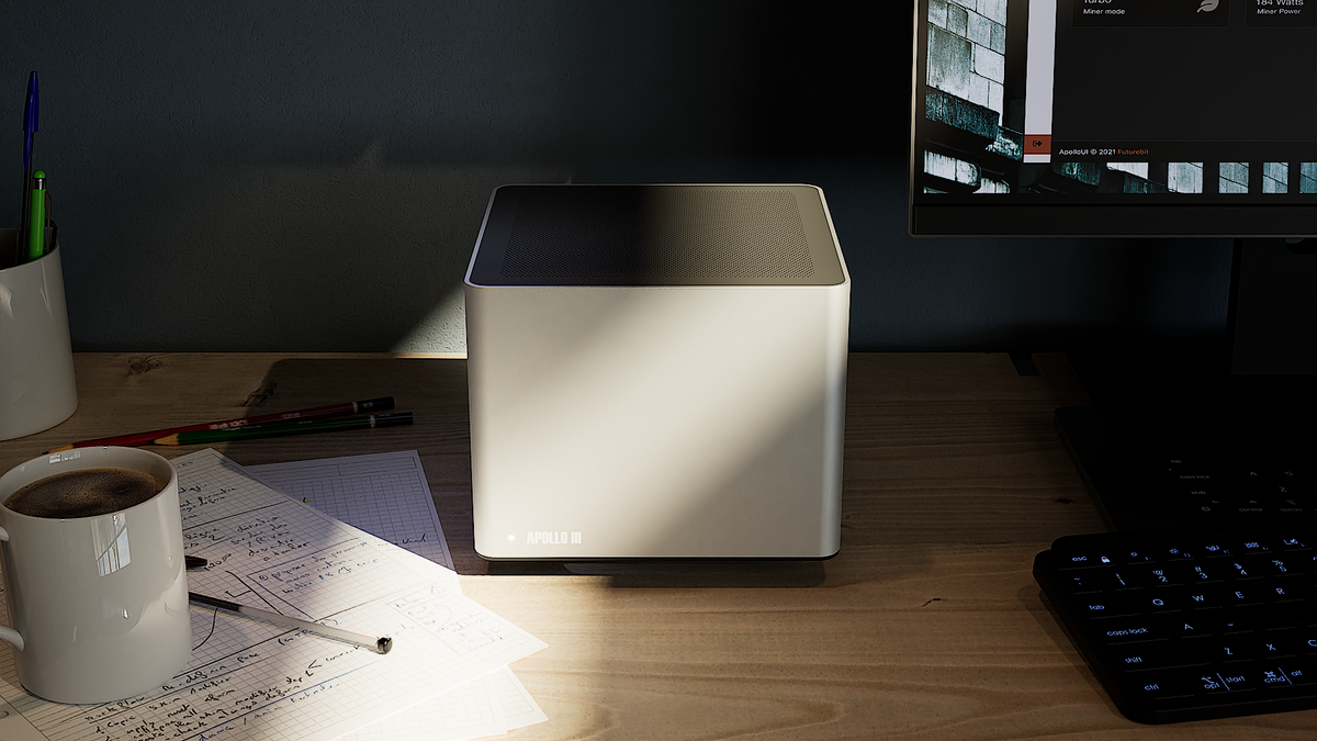 Apollo III on a desk next to a coffee mug and keyboard, showing its compact 6-inch cube size